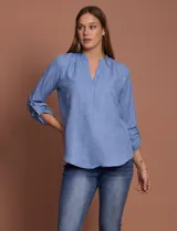 Blusa celeste con escote en V y mangas 3/4 regulables con presilla y botón.