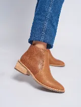 Bota corta de cuero color marrón claro, con puntera redondeada, cierre lateral invisible y taco de madera.