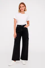 Pantalón cargo de jean color negro con corte ancho, bolsillos laterales y detalle de tachas plateadas en los laterales.