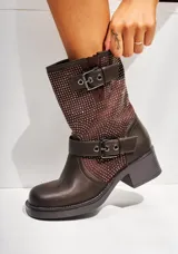 Bota corta de cuero color chocolate con apliques de tachas pequeñas. Tiene cierre lateral y correa con hebilla alrededor del tobillo.