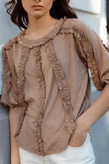 Blusa color beige de manga 3/4 confeccionada en algodón suave, con escote a la base y detalles de volados en 3D que recorren el frente, mangas y escote.