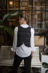 Chaleco negro con diseño tweed, cuello redondo y espalda irregular. Se puede usar solo como top o sobre una camisa.