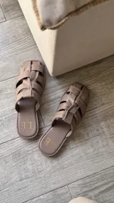 Sandalias bajas color rosa viejo con tiras de cuero entrelazadas y suela marrón.