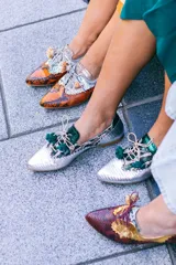 Zapato blucher de cuero con estampado animal print en tonos naranja y plateado, con cordones y detalle de borlas.