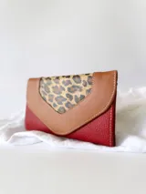 Billetera de cuero color rojo con solapa de cuero color marrón y aplique de cuero con estampado animal print.