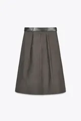 Falda midi color blanco hueso, de tiro alto y corte evasé. Incluye cinturón negro con hebilla metálica.