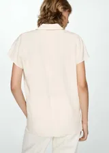 Camisa verde esmeralda de corte recto, con cuello camisero, mangas cortas y cierre frontal con botones.