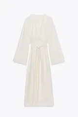 Vestido midi color crudo, con escote en V y mangas largas acampanadas. Cintura ajustable con lazos del mismo tejido.