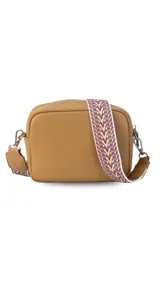 Bandolera pequeña de símil cuero color camel, con dos compartimentos principales con cierre. Incluye una correa ancha de tela estampada con motivos geométricos en tonos tierra y blanco.