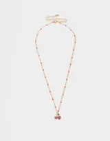 Collar corto dorado con cadena de eslabones y cuentas rosadas. Dije de cerezas con incrustaciones de strass fucsia y hoja verde.