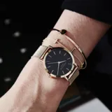 Reloj Rosefield con caja redonda de acero rosado de 33 mm, esfera negra minimalista y malla metálica rosada.