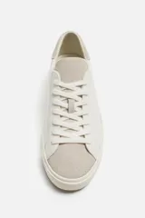 Zapatillas blancas de cuero con detalles en gamuza en la puntera y el talón. Cierre con cordones.