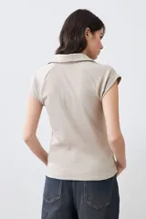 Remera de punto canalé color beige melange, con cuello polo y mangas cortas.