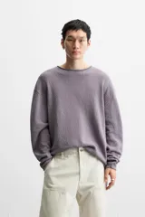 Jersey de hombre color lila, tejido en hilatura de algodón con textura. Tiene cuello redondo, manga larga y acabados en rib con detalle de vuelta.