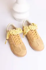 Zapatillas bajas de gamuza celeste con cordones y pañuelos estampados atados a los cordones.