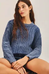 Sweater celeste de punto con diseño de trenzas, cuello redondo y corte holgado.