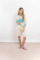 Sweater tejido de lana merino color crudo, con cuello, puños y ruedo acanalados en color celeste. Presenta un corazón celeste tejido en el frente.