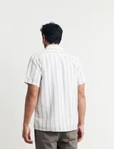 Camisa de manga corta a rayas verticales celestes y blancas, con cuello clásico y botones marrones.