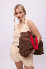 Bolso tote de lona color beige claro con asas negras. Presenta un estampado de texto curvo en negro en el frente que dice "BeGanesha".