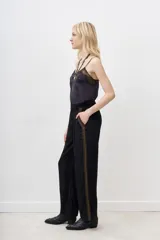Pantalón negro de viscosa con aplicación de lentejuelas doradas en los laterales.