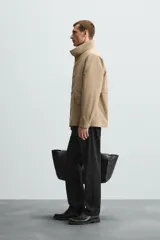 Parka ligera color beige, de corte relaxed fit, confeccionada en tejido técnico repelente al agua. Tiene cuello alto, mangas largas con puños ajustables con botón a presión, bolsillos de solapa en la cadera y cierre frontal con cremallera oculta por solapa con botones a presión.