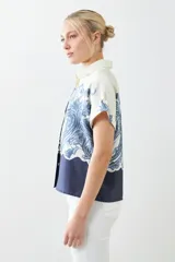 Camisa de manga corta con estampado paisley en tonos azul y blanco, con cuello clásico y cierre con botones.