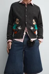 Cárdigan gris oscuro de lana con cuello redondo y cierre frontal con botones. Tiene estampado de Mickey Mouse en el frente.