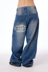 Jean oversized de tiro bajo, color azul lavado, con estampa BLKMBA grabada con láser en el frente y estampa worldwide en la parte trasera.