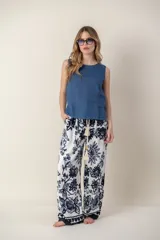 Pantalón ancho de tela blanca con estampado de flores azules, cintura alta con cordón ajustable y bolsillos laterales.