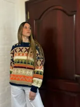 Sweater de lana merino con cuello redondo y diseño con motivos geométricos en tonos azul, marrón, naranja, verde y beige.