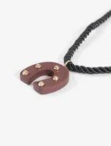 Collar con cordón negro y dije de herradura marrón con apliques dorados.