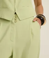 Pantalón zanahoria de vestir color verde claro, de tiro alto, con pliegues y bolsillos laterales.