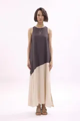 Vestido largo sin mangas, con corte diagonal a la altura de la cadera que combina una parte superior gris oscuro y una falda color crema.