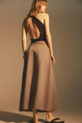 Falda midi color beige confeccionada en hilatura con viscosa. Tiene tiro alto, cintura con trabillas ajustable con lazada en el mismo tejido, detalle de doble pliegue en el delantero y bajo acabado con costuras marcadas a tono. Cierre lateral con cremallera oculta.