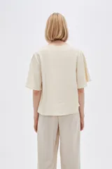 Blusa color crema de viscosa con escote en V y mangas cortas acampanadas.