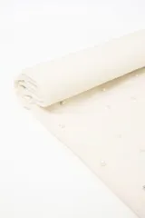 Pashmina color blanco roto con flecos en los extremos y decorada con perlas pequeñas. Incluye un parche de cuero sintético marrón con un logo grabado.