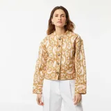Chaqueta corta acolchada color beige con estampado abstracto en blanco, cuello redondo y cierre frontal con botones.