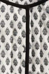 Campera corta acolchada de algodón con estampado floral en blanco y negro, cuello redondo, cierre frontal con botones a presión, bolsillos delanteros de parche y forro de algodón.
