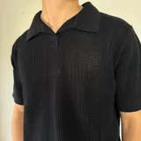 Chomba negra tejida con cuello polo y corte regular.