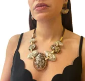 Collar corto con cordón marrón y piezas ovaladas de resina color marrón y blanco con detalles dorados, unidas por eslabones dorados. Diseño italiano de Fahoma.