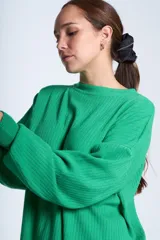 Sweater color beige de tejido de punto acanalado, con cuello redondo y mangas largas. Tiene corte holgado y aberturas laterales en el ruedo.