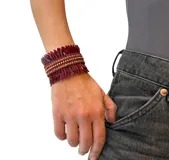 Pulsera tipo brazalete color borgoña con lentejuelas delgadas y strass dorados.