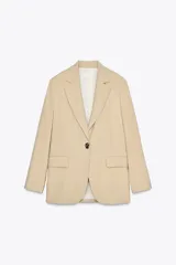 Blazer color beige confeccionada con lino, de corte recto, con cuello solapa, manga larga con hombreras, bolsillos delanteros con solapa y cierre frontal con un botón grande.