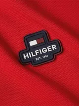Chomba roja de Tommy Hilfiger, de corte regular, confeccionada en mezcla de algodón y elastano. Presenta cuello estilo chomba con botones, logo de la marca bordado en el pecho y bandera bordada en la manga.