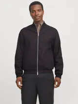 Campera bomber negra de tejido liviano de lino y algodón, con cuello tipo baseball, cierre con cremallera, mangas largas con puños de canalé y bolsillos delanteros.
