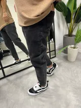 Pantalón de jean negro gastado, corte slouchy, tiro alto y tobillos ajustados.