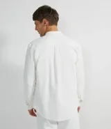 Camisa blanca de manga larga, confeccionada en terciopelo con cuello clásico y bolsillos frontales.