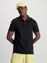 Chomba negra de piqué de algodón peinado, corte regular, cuello clásico con dos botones, mangas cortas, dobladillo con aberturas laterales y logo de Calvin Klein en la manga.