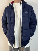 Campera inflada color ocre con capucha, cierre frontal con cremallera y logo de la marca bordado en el pecho.