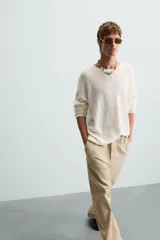 Pantalón de algodón color beige con efecto lavado, corte relajado y pierna ancha. Presenta cintura elástica con ajuste de cordón y cierre frontal con botón, además de bolsillos delanteros y bolsillos traseros de plastrón.